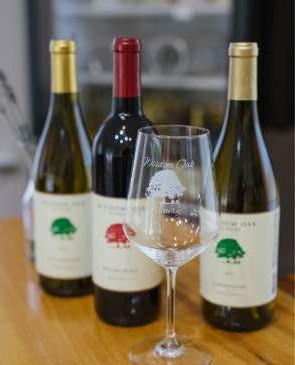 Wisdom Oak Winery glass with 3 bottles behind